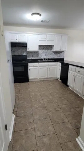 a kitchen with granite countertop a stove a sink and a refrigerator