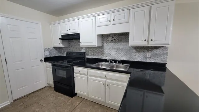 a kitchen with granite countertop white cabinets and stainless steel appliances