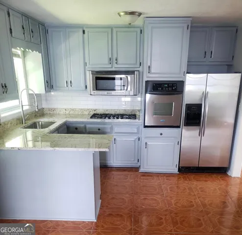 a kitchen with stainless steel appliances granite countertop a refrigerator sink and stove