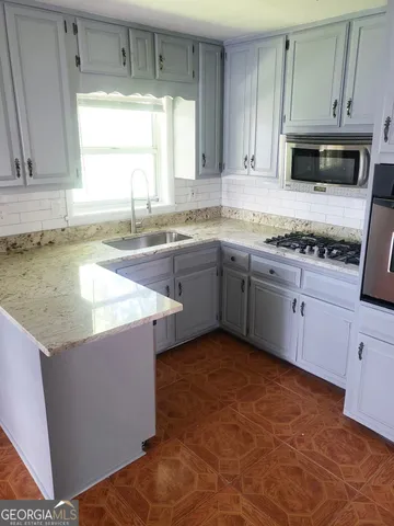 a kitchen with stainless steel appliances granite countertop a stove a sink and a microwave
