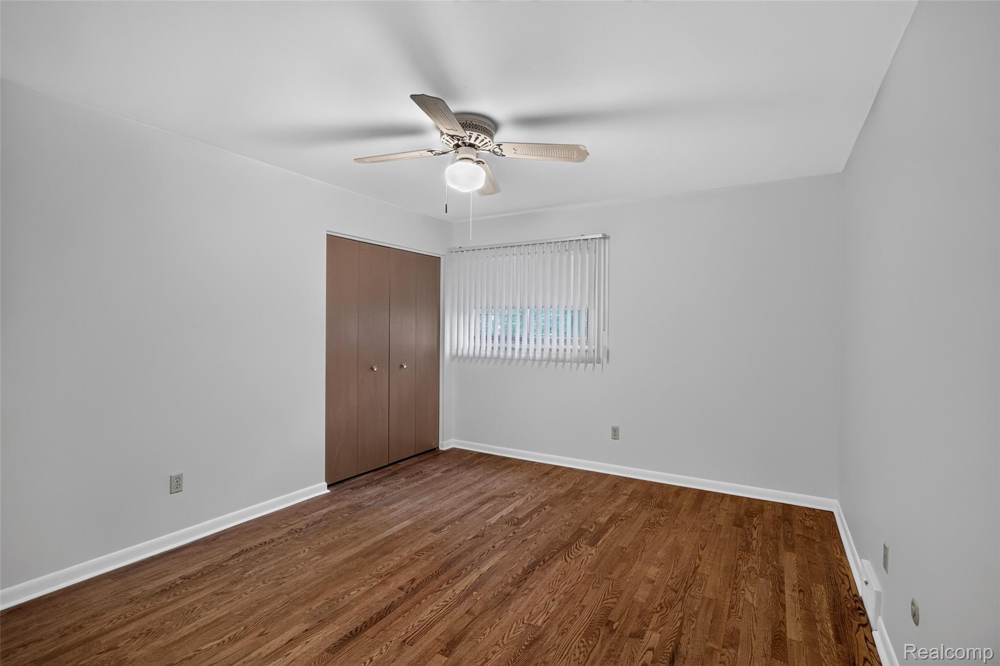1225 Derby Road, Unit 3 Birmingham, MI 48009 - Photo 13 of 19 Spacious bedroom showcasing rich looking floors, neutral walls, and abundant natural light from a large window with vertical blinds