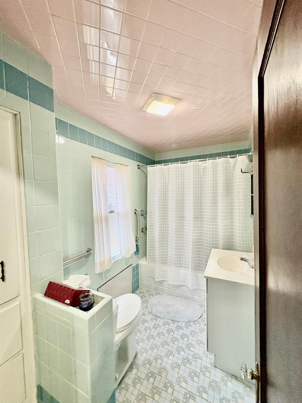 123 Rockland Road Roscoe, NY 12776 - Photo 20 of 31 Bathroom with toilet, shower / tub combo with curtain, vanity, tile patterned flooring, and tile walls