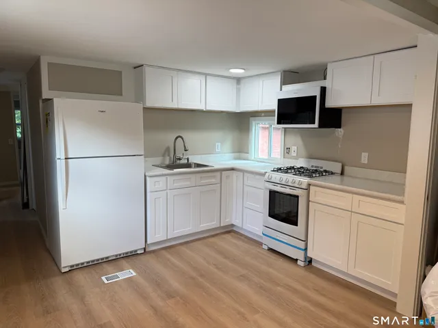 a kitchen with white cabinets and white appliances