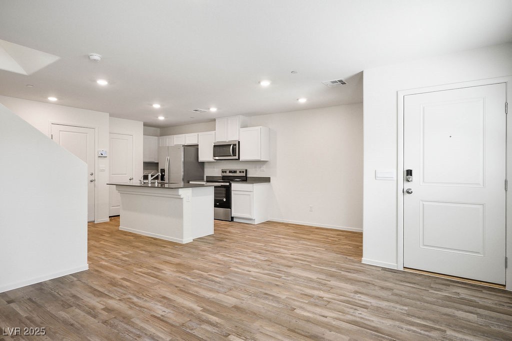 6184 Hibiscus Gdn Street North Las Vegas, NV 89081 - Photo 5 of 35 Kitchen with white cabinets, dark countertops, a kitchen island with sink, recessed lighting, and stainless steel appliances