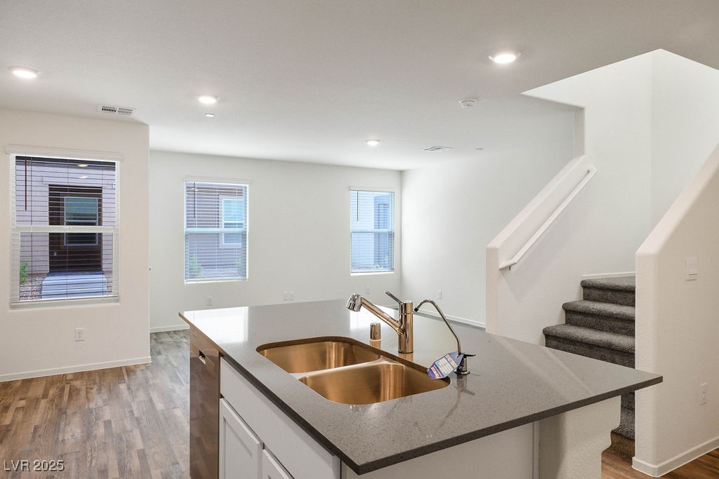 6184 Hibiscus Gdn Street North Las Vegas, NV 89081 - Photo 10 of 35 Kitchen featuring dark stone counters, light wood-type flooring, white cabinets, a center island with sink, and recessed lighting