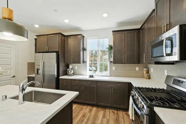 a kitchen with stainless steel appliances granite countertop a sink stove and refrigerator