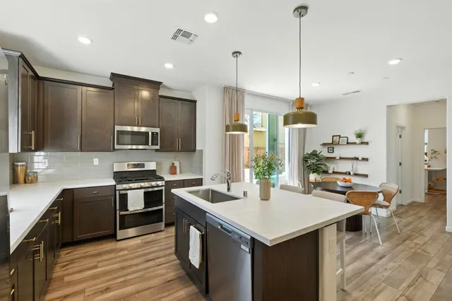 a kitchen with stainless steel appliances granite countertop a sink a stove and a wooden floors