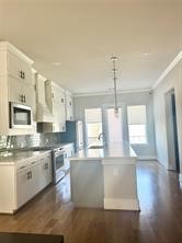 1315 West 24th Street, Unit B Houston, TX 77008 - Photo 11 of 26 a large kitchen with granite countertop a stove a sink a refrigerator and white cabinets with wooden floor