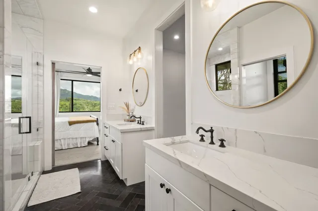a en suite bathroom with a double vanity sink a mirror a window and a shower