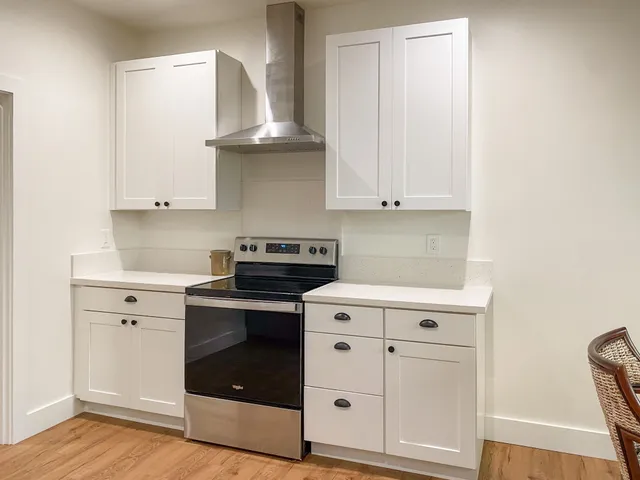 a kitchen with granite countertop white cabinets and a stove