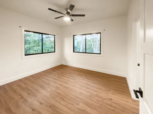 a view of an empty room with wooden floor and a window