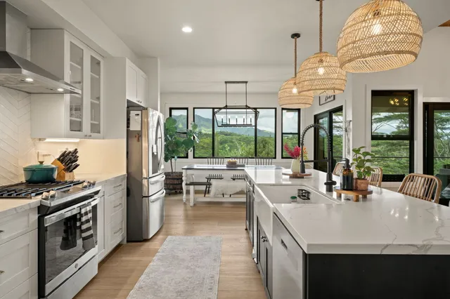 a kitchen with a sink stainless steel appliances a large window and cabinets