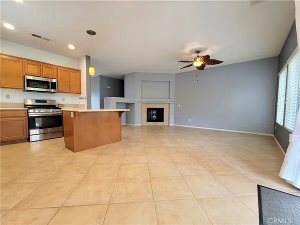 a living room with stainless steel appliances furniture a fireplace and a window