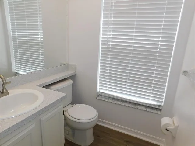 a bathroom with a toilet a sink a mirror and a window