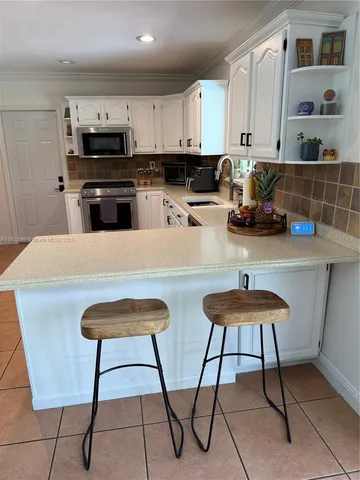 a kitchen with stainless steel appliances a stove a sink a microwave and a refrigerator