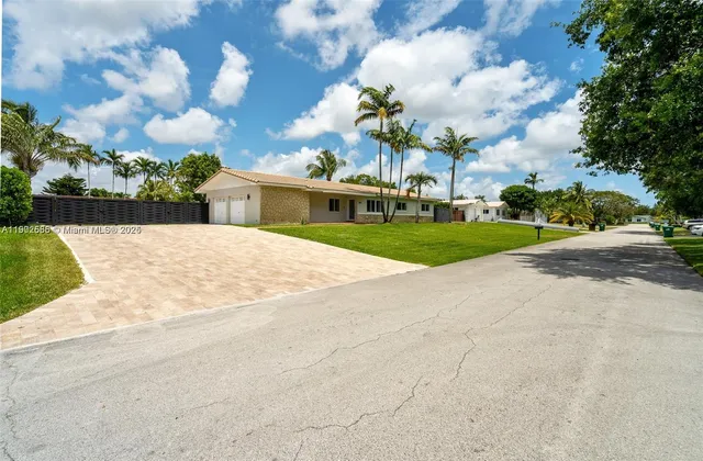 a view of a white house with a big yard plants and trees