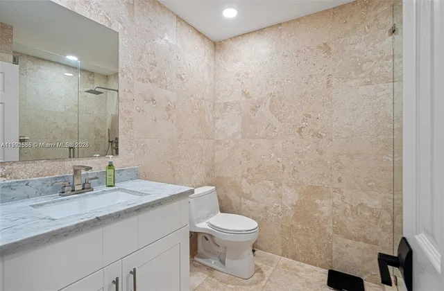 a bathroom with a granite countertop sink a toilet and a mirror