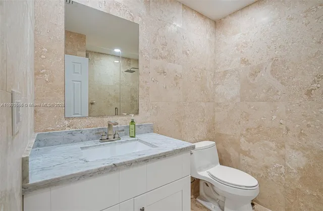 a bathroom with a granite countertop sink a toilet and a mirror