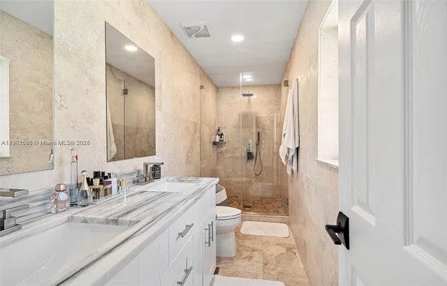 a bathroom with a double vanity sink toilet mirror and shower