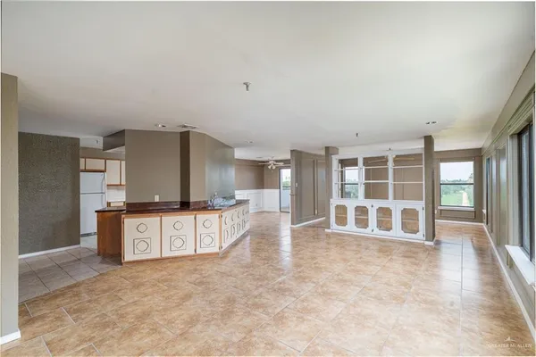 a large white kitchen with granite countertop a large counter top space a sink stainless steel appliances and cabinets