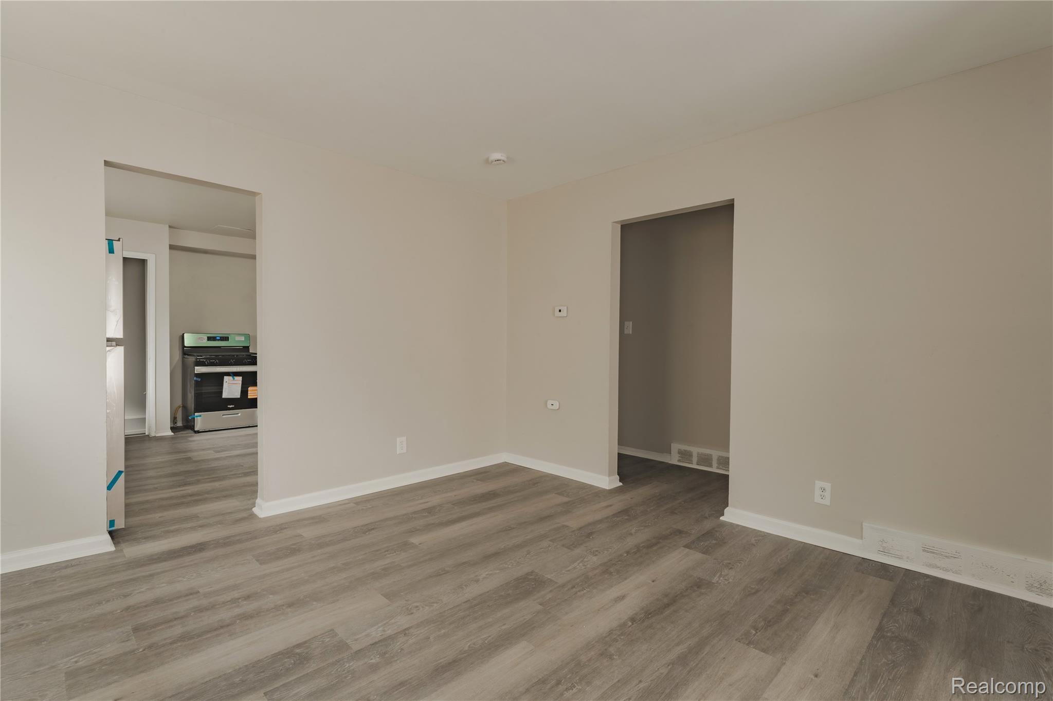 93 West Princeton Avenue Pontiac, MI 48340 - Photo 6 of 31 Interior space featuring wood-finish flooring, light neutral wall tones, white baseboards, and two open doorways