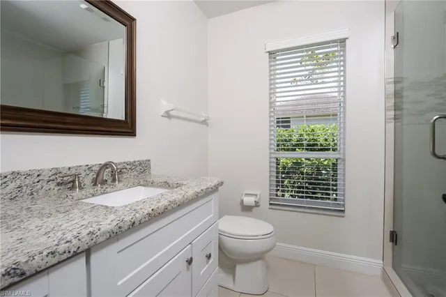 a bathroom with a granite countertop toilet a sink a mirror and a window