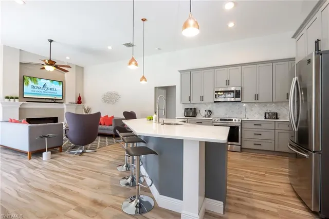 a kitchen with stainless steel appliances kitchen island granite countertop a sink dishwasher a refrigerator and a stove with wooden floor