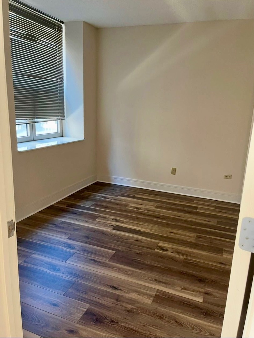 222 North Columbus Drive, Unit 806 Chicago, IL 60601 - Photo 7 of 16 a view of an empty room with wooden floor and a window