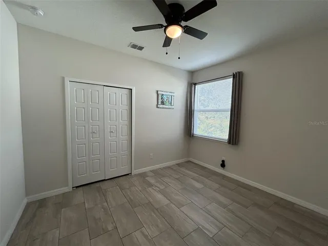 an empty room with fan and windows