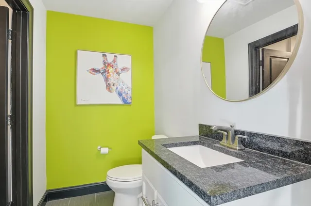 a bathroom with a granite countertop toilet sink and mirror