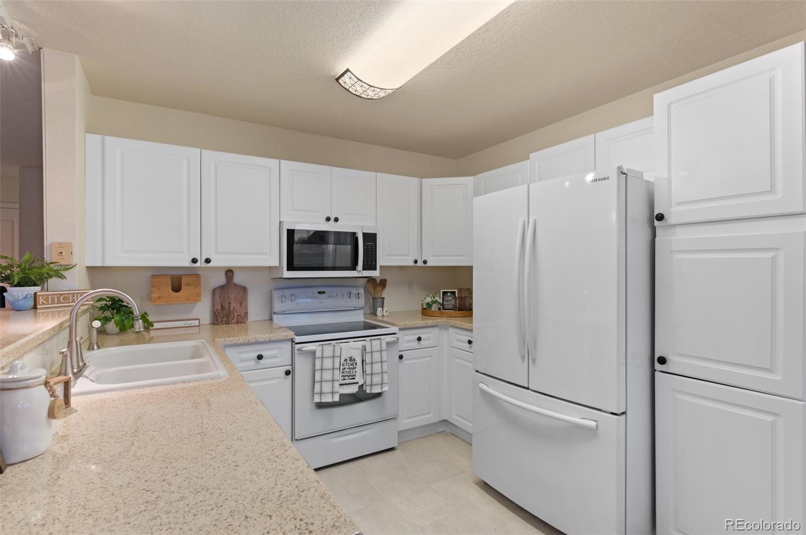 12734 Eudora Drive Thornton, CO 80241 - Photo 12 of 49 a kitchen with stainless steel appliances a refrigerator sink and white cabinets