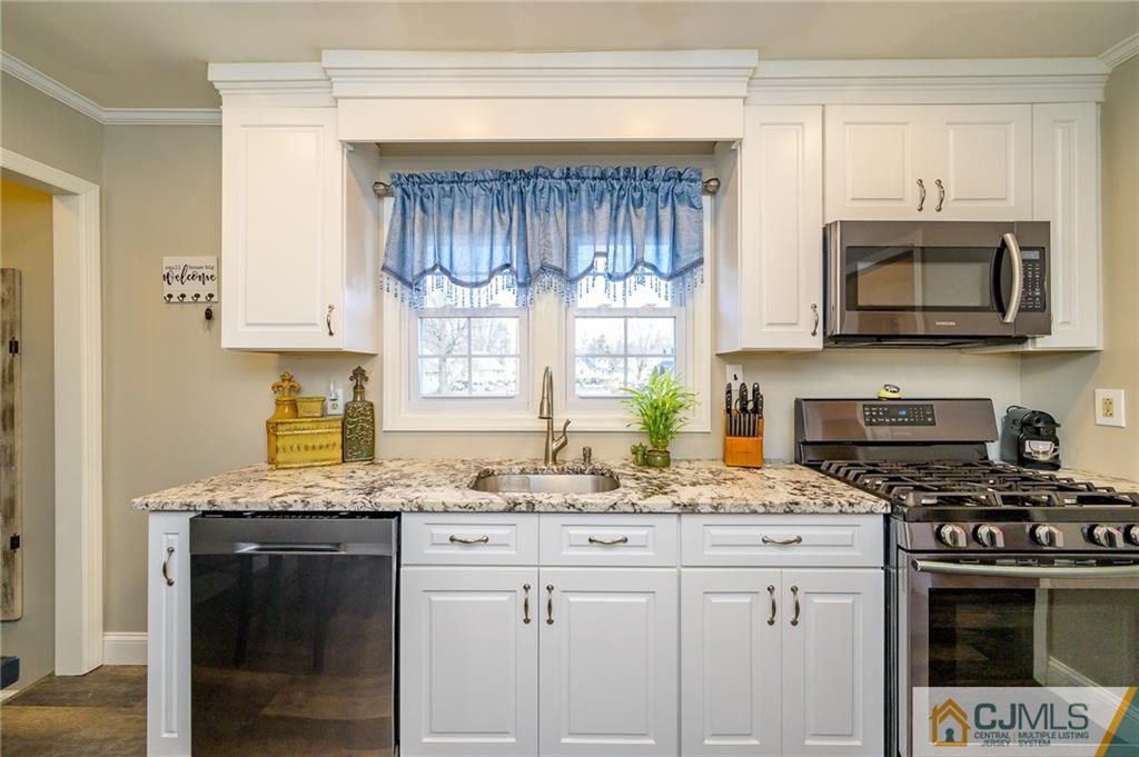 14 Sine Road Edison, NJ 08817 - Photo 10 of 33 a kitchen with granite countertop a stove a sink and a microwave