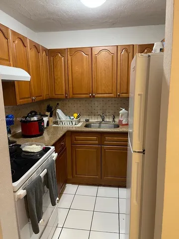 a kitchen with a refrigerator a stove a sink and cabinets