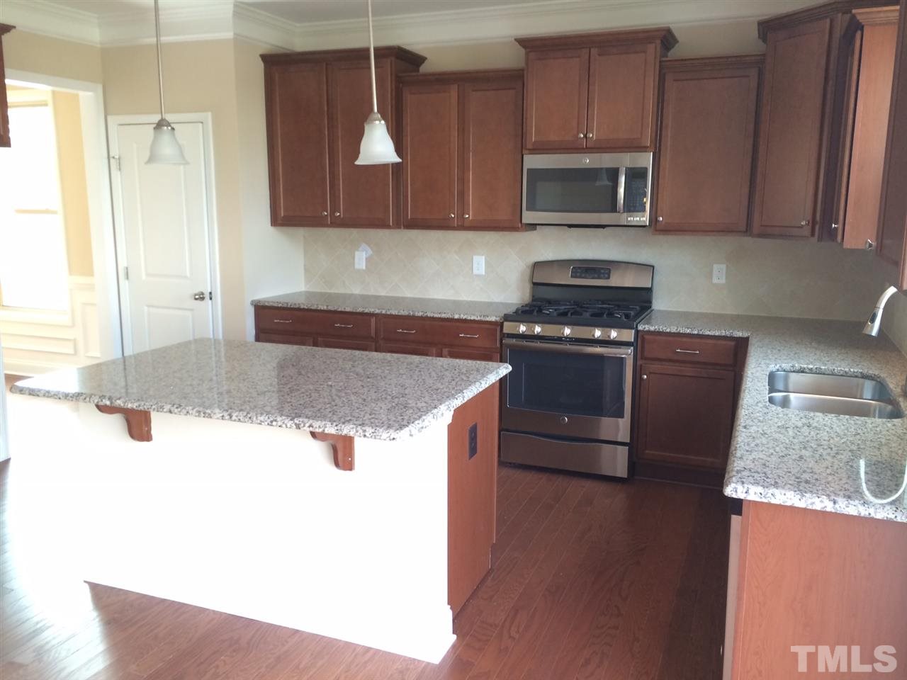 7609 Channery Way Raleigh, NC 27616 - Photo 6 of 25 a kitchen with granite countertop a stove and a microwave with cabinets