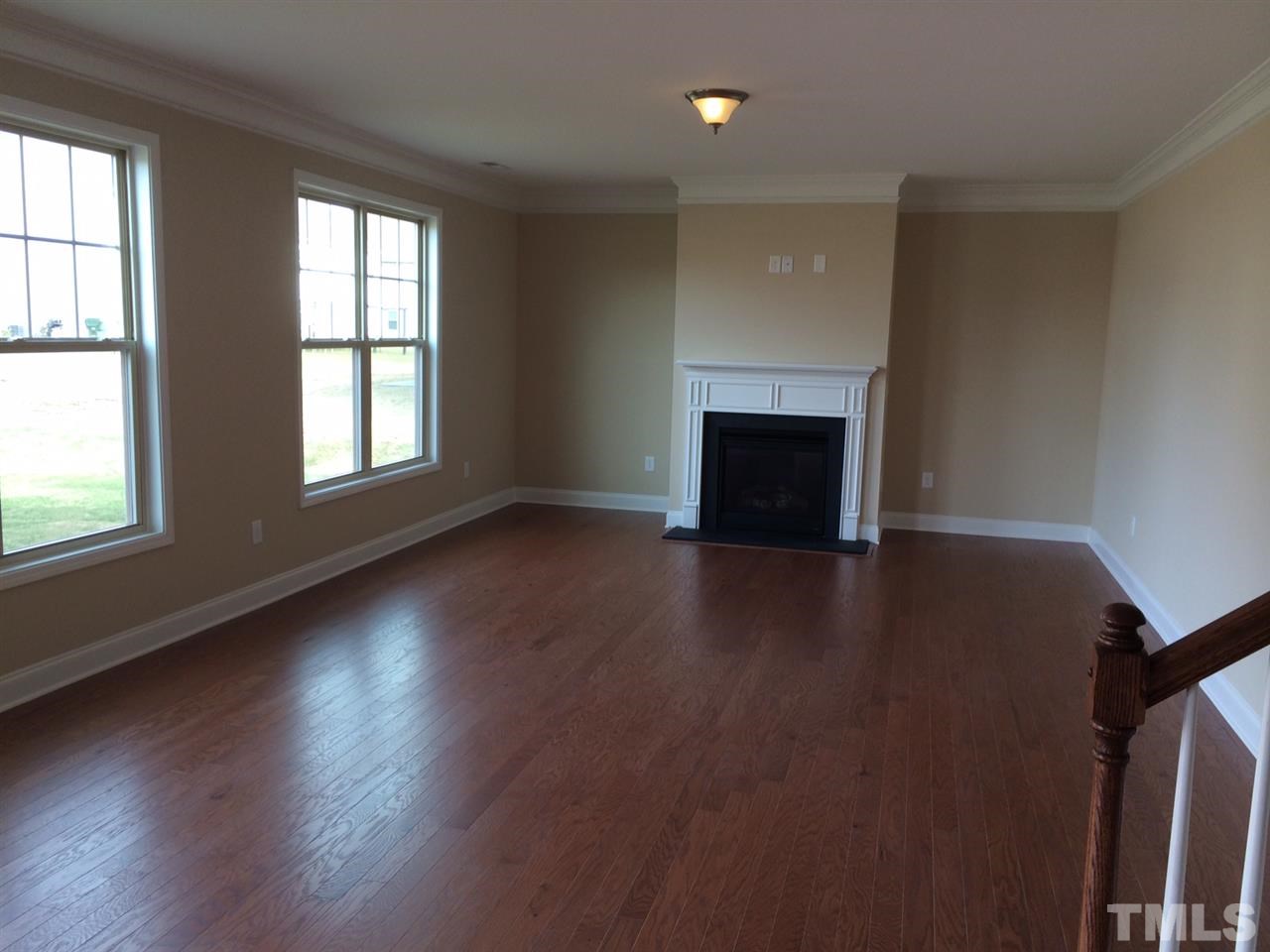 7609 Channery Way Raleigh, NC 27616 - Photo 9 of 25 an empty room with wooden floor fireplace and windows