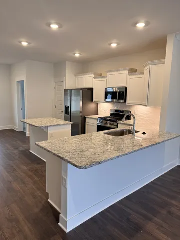 a kitchen with stainless steel appliances granite countertop a sink a stove a refrigerator and a oven