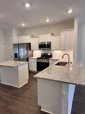 a kitchen with kitchen island granite countertop a sink wooden cabinets and stainless steel appliances