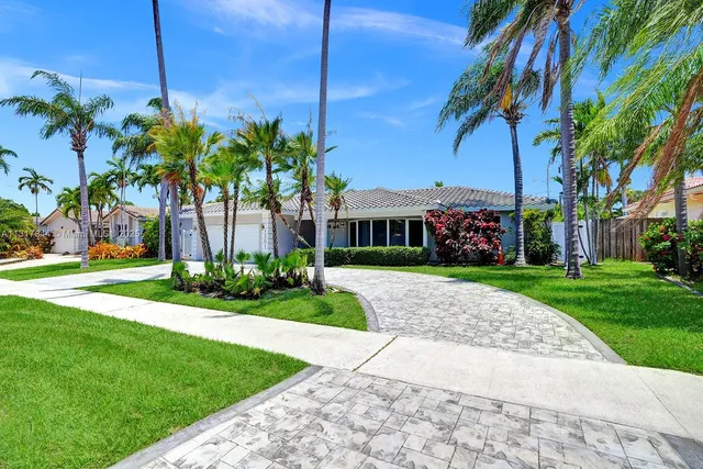 a front view of a house with a garden and palm trees