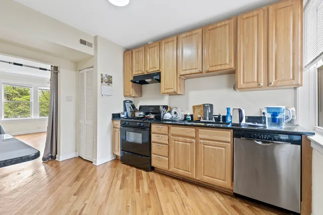 a kitchen with granite countertop wooden floors and white stainless steel appliances