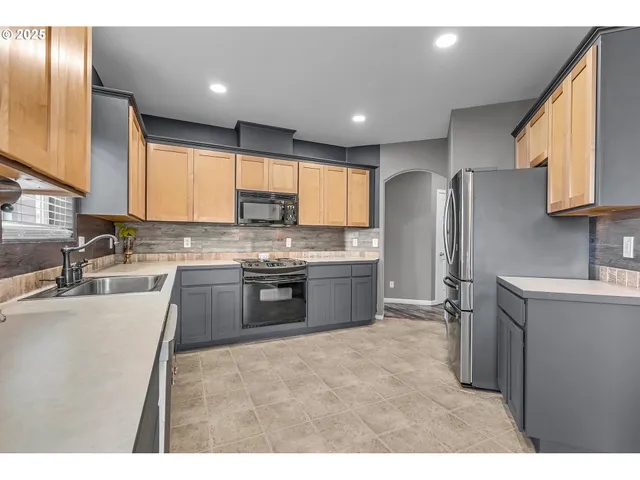 a kitchen with stainless steel appliances granite countertop a refrigerator sink and wooden cabinets