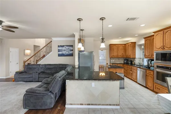 a large kitchen with stainless steel appliances kitchen island granite countertop a refrigerator a stove and a sink with wooden floor