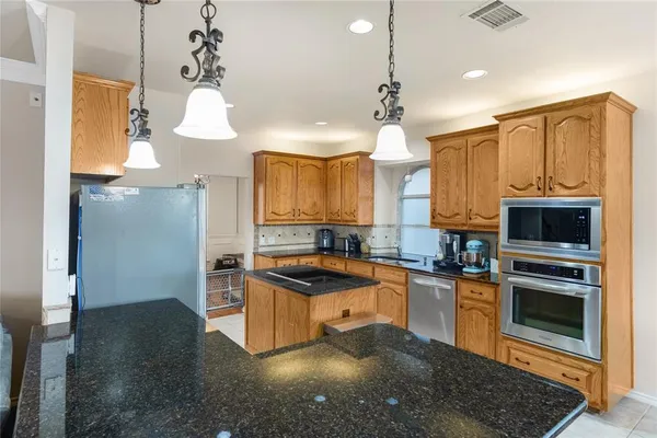 a kitchen with granite countertop a stove a sink and a refrigerator