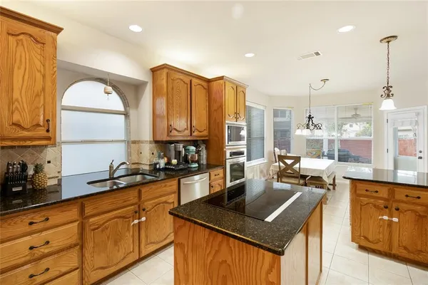 a kitchen with kitchen island granite countertop a sink a counter space appliances and cabinets