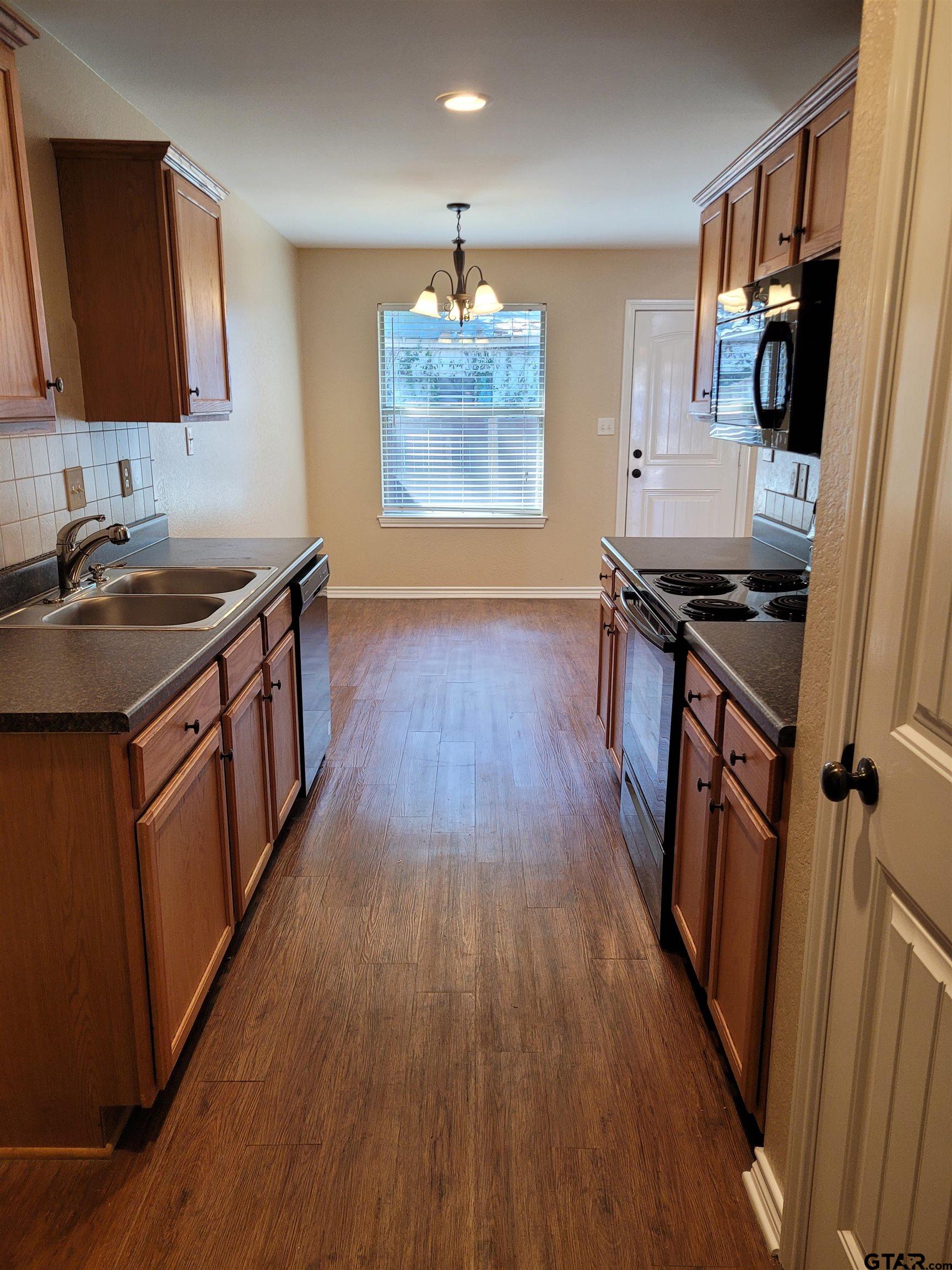 19054 County Road 1202 Flint, TX 75762 - Photo 8 of 19 a kitchen with wooden floors wooden cabinets a sink a stove and a window