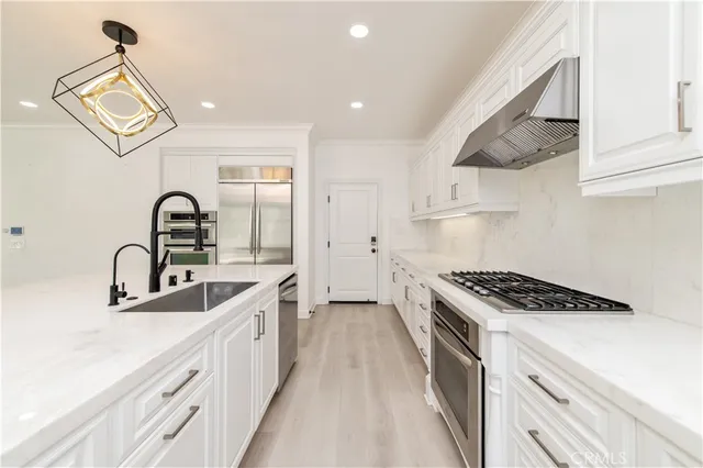 a kitchen with kitchen island stainless steel appliances a sink a stove and a wooden floors