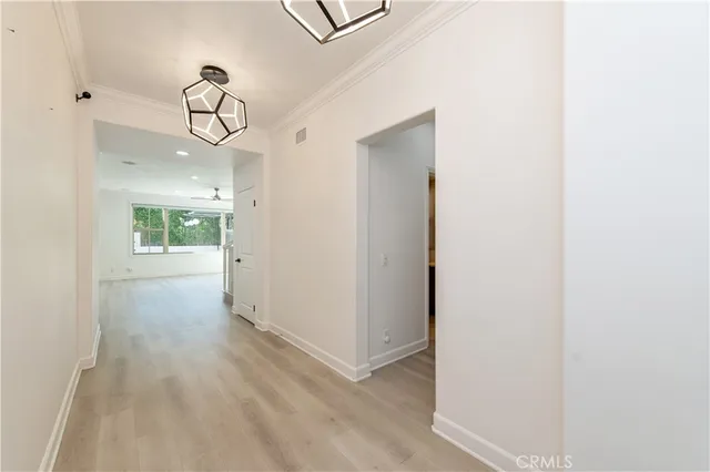 a view of a hallway with wooden floor and chandelier