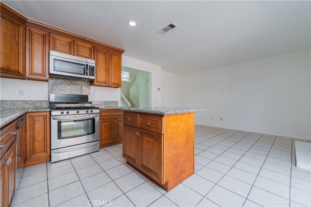 498 Monroe, Unit 15 Irvine, CA 92620 - Photo 6 of 26 a kitchen with stainless steel appliances granite countertop a stove a sink and a microwave