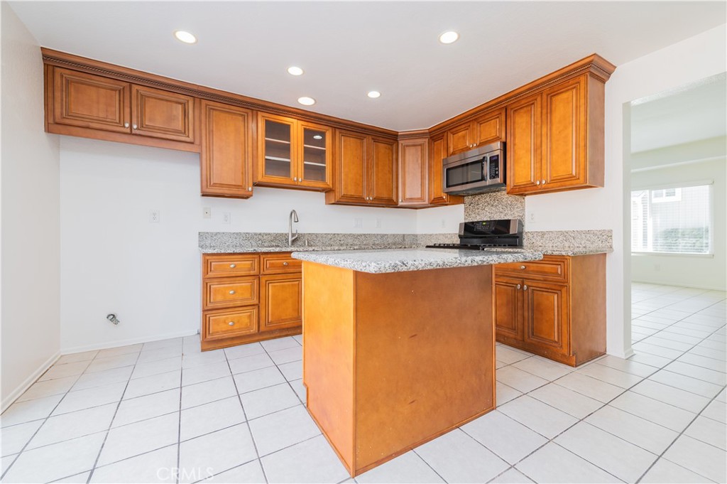 498 Monroe, Unit 15 Irvine, CA 92620 - Photo 8 of 26 a kitchen with stainless steel appliances granite countertop a stove a sink and a microwave