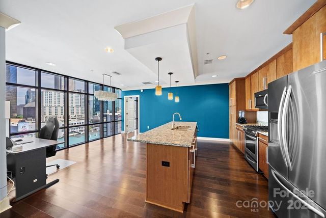 a kitchen with stainless steel appliances granite countertop a refrigerator a stove and a wooden floors