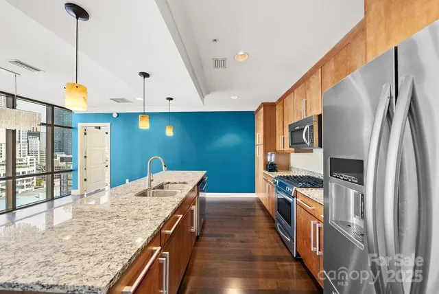 a kitchen with stainless steel appliances granite countertop a refrigerator a oven and a sink